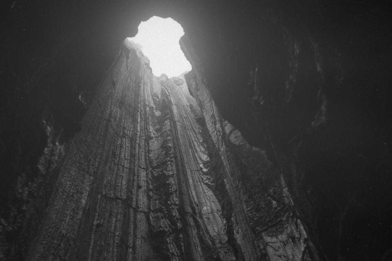 A shaft of black stone opens upwards to the light.