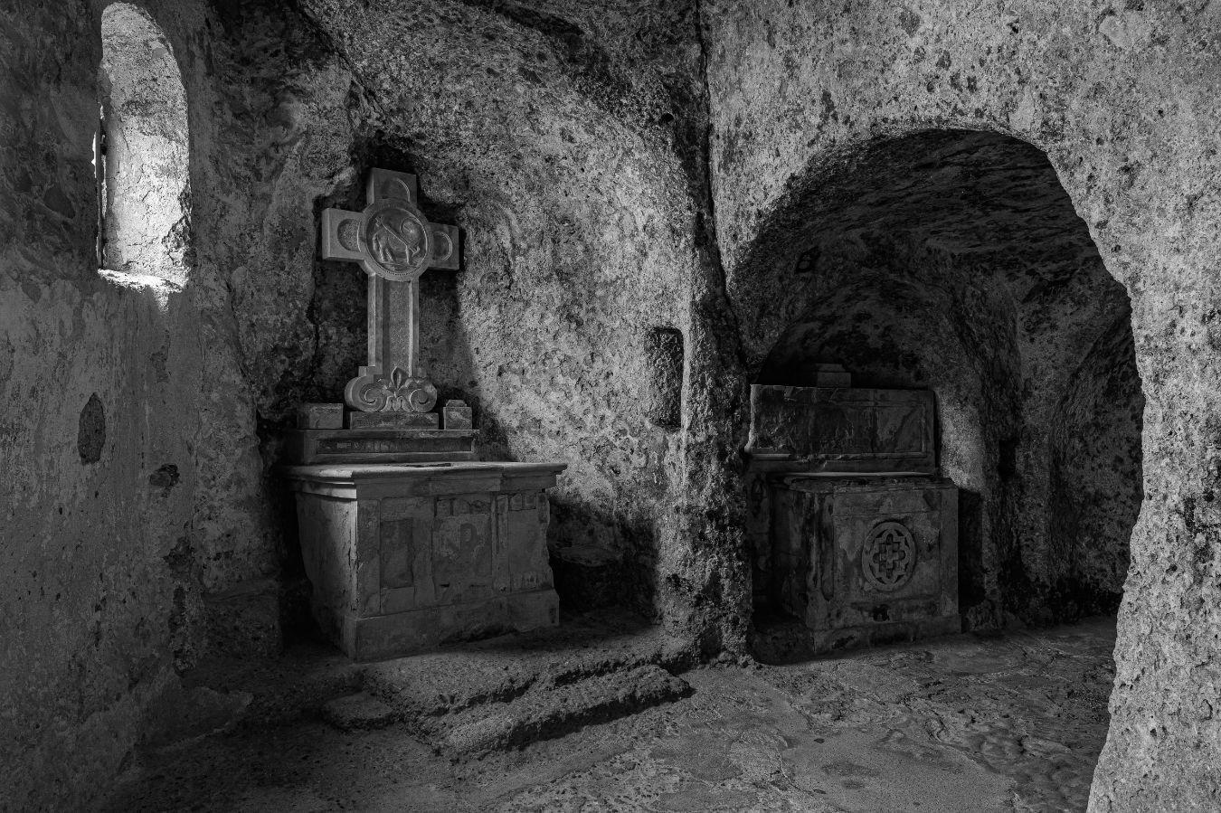 A low room carved into the stone with a stone cross.