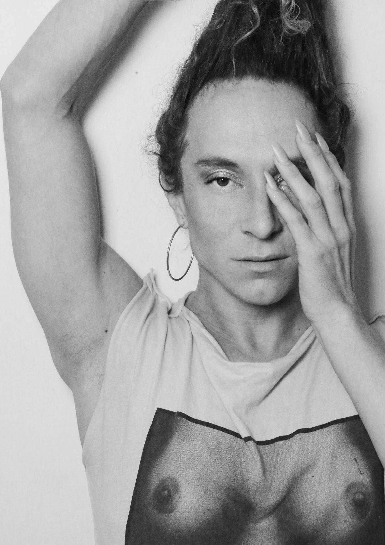 Chaignaud holds a hand over one part of the face. Chaignaud wears long fingernails.