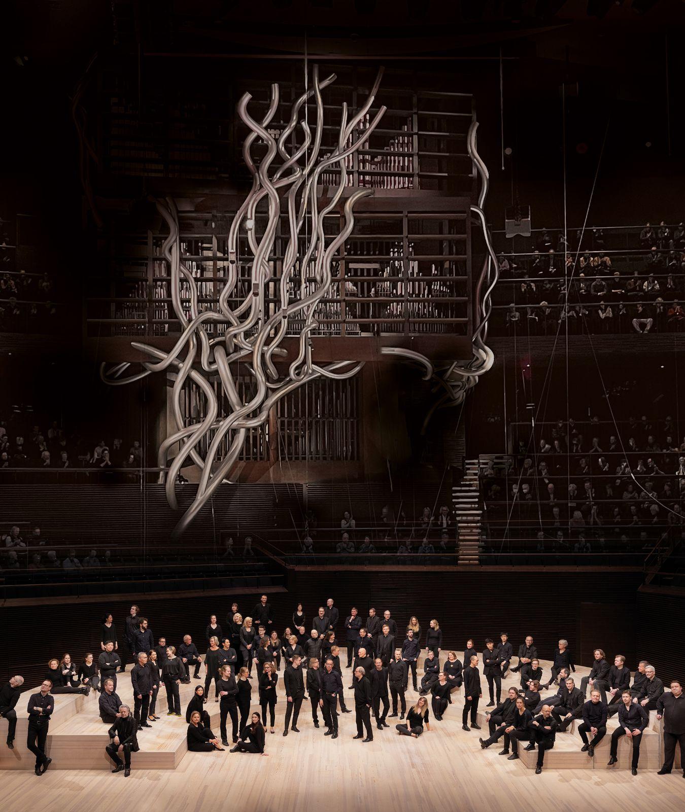 The Finnish Radio Symphony Orchestra stands beneath the large stage decoration of an artificial, abstract tree.