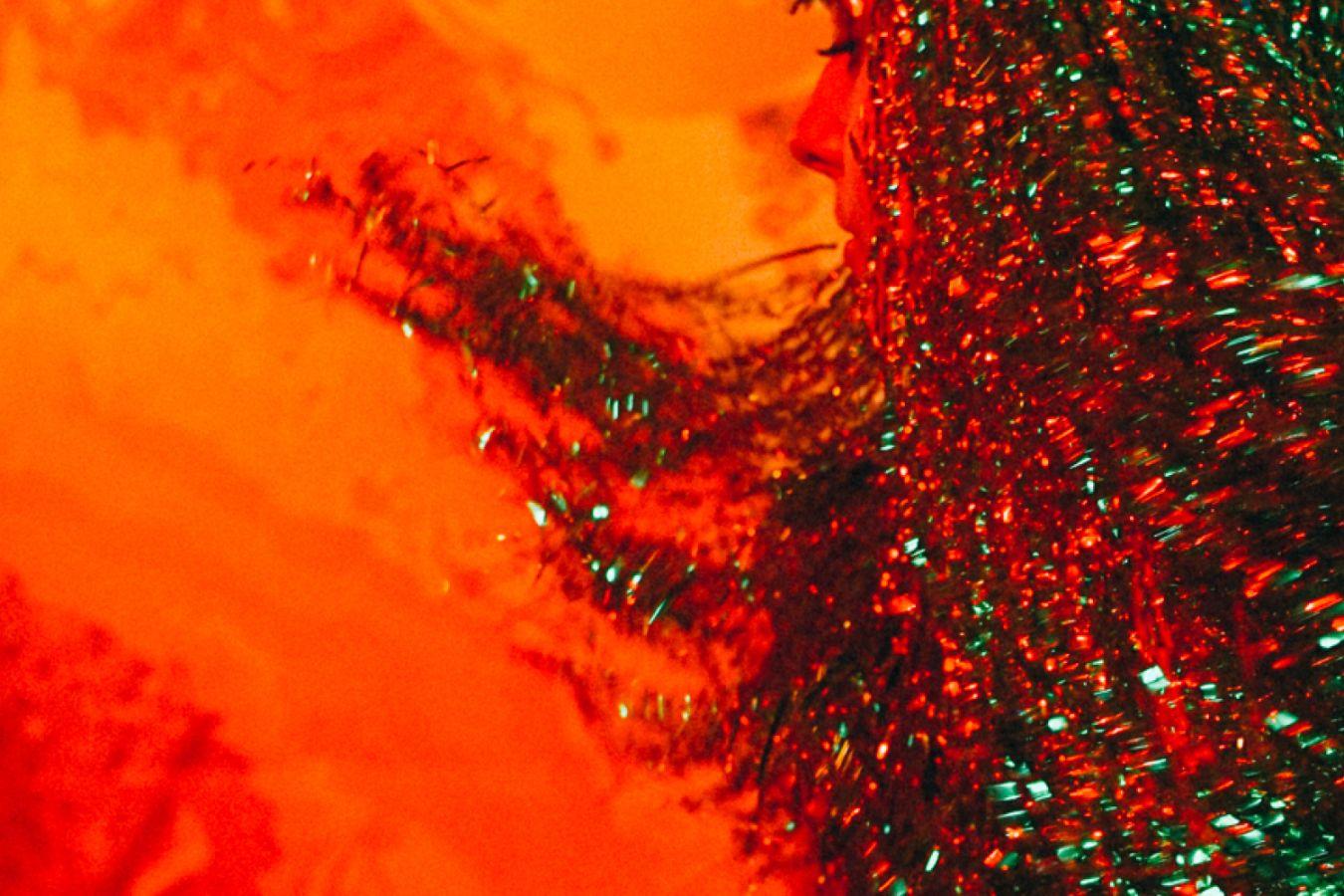 Glitzerperücke vor orangem Hintergrund