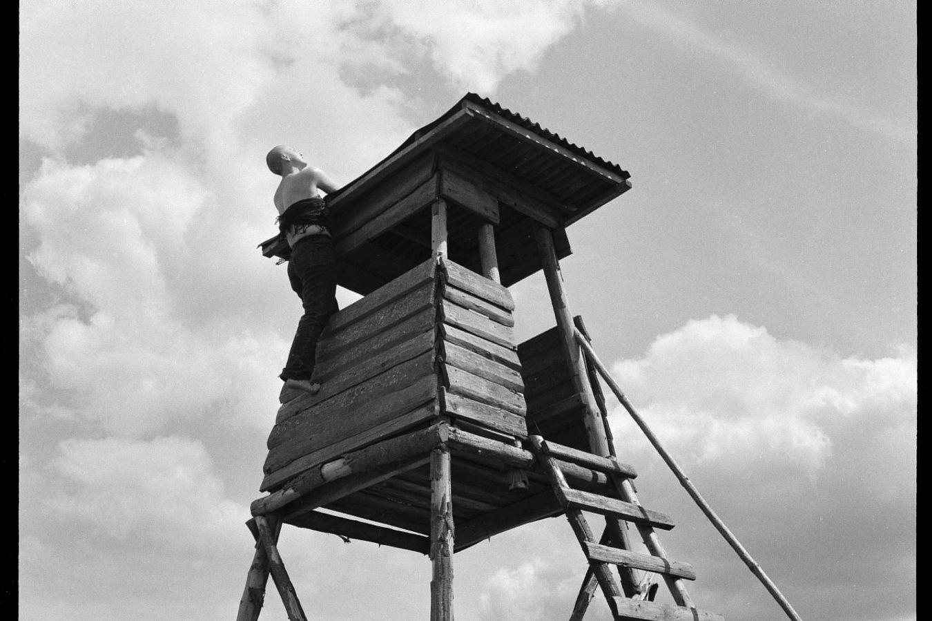 A woman climbs a high stand with her bare feet.