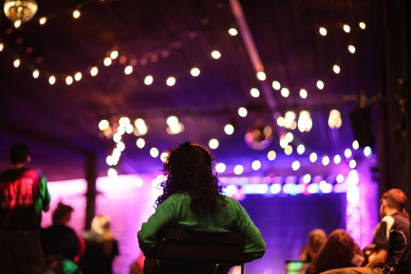 A party in the Haus der Berliner Festspiele. Colourful fairy lights hang from the rafters.