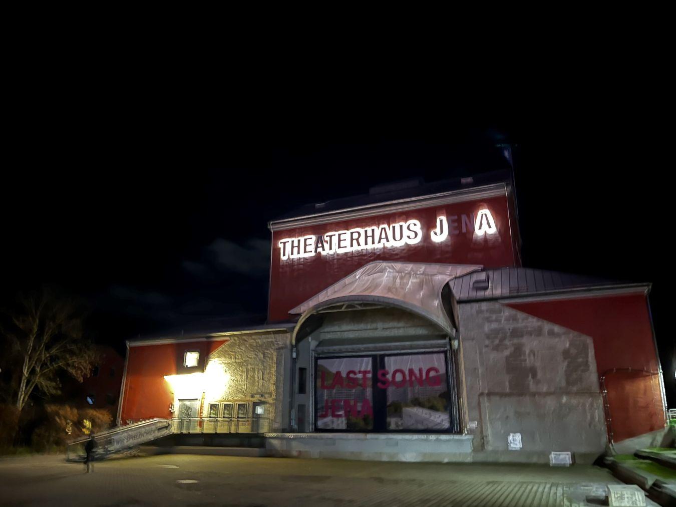Exterior view of the Jena Theatre with a partially non-functioning neon sign on the roof