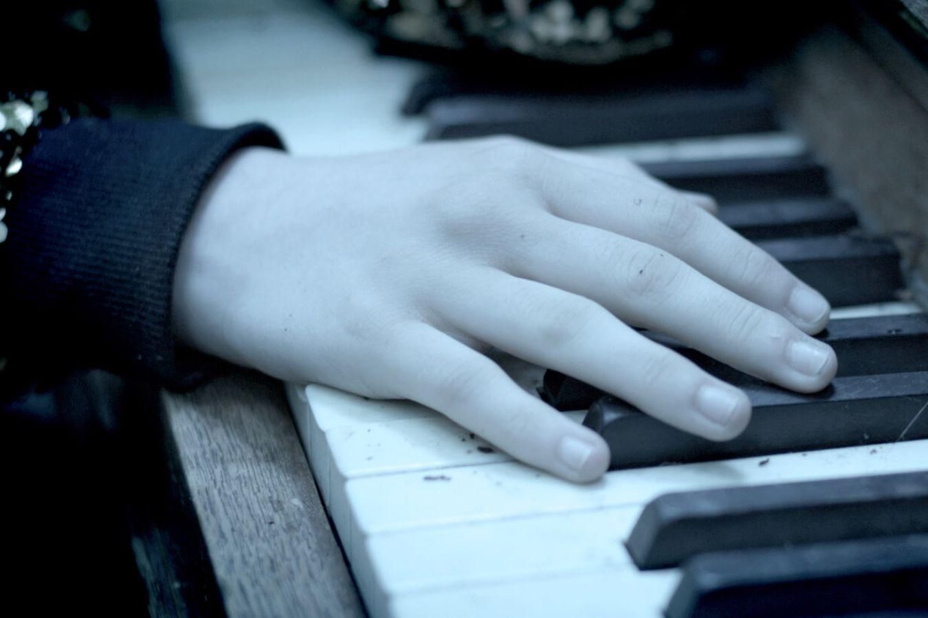 A hand rests on the keys of a piano.