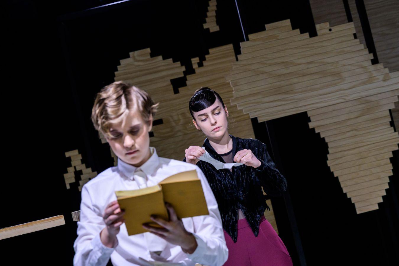 Zwei junge Frauen in altmodischen Kostüumen lesen jede in einem Buch. Die eine Frau ist im Vordergrund des Bildes und unscharf. Die zweie Frau steht weiter im Hintergrund und ist klar zu erkennen.