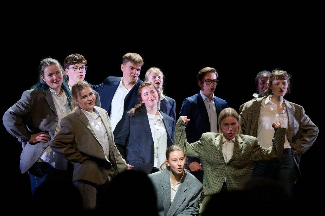 Eine Gruppe junger Menschen posieren in grauen und bauen Anzug-Sakkos.