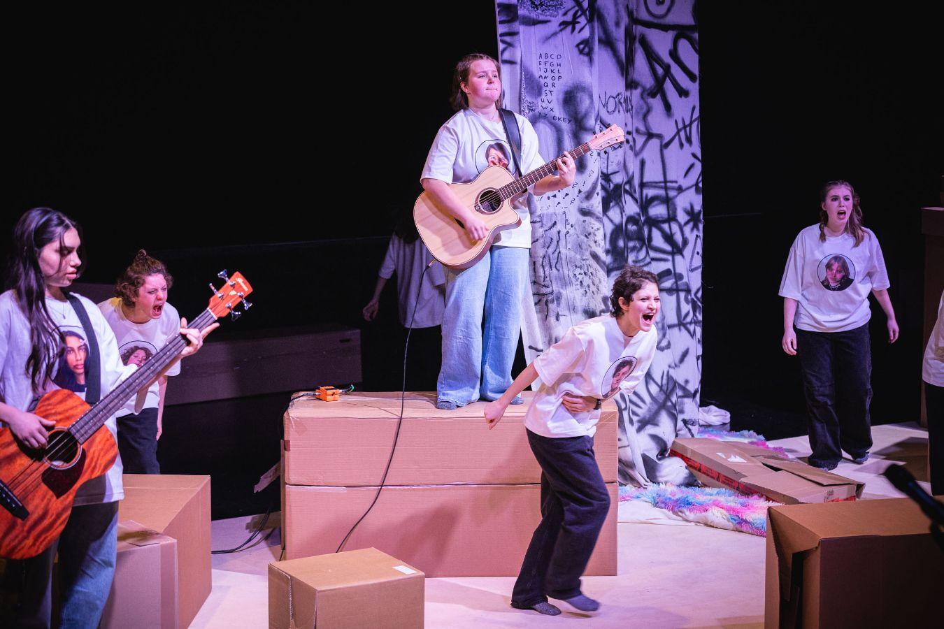 The ensemble standing on stage with music instruments.