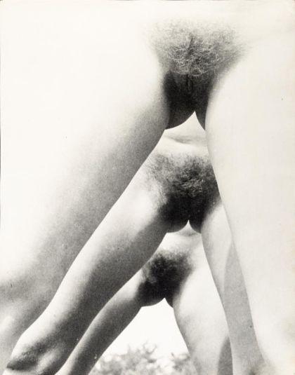 Black‑and‑white photograph showing three pairs of legs spread apart and positioned one behind the other in a receding perspective, opening the view between the legs on the vulvas.