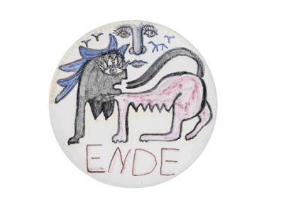 A circular object featuring hand-drawn, colored imagery. Two stylized, animal-like figures in black, blue, and pink face each other and partially overlap. Linear, sketch-like markings appear between the figures. The handwritten word “ENDE” is visible along the lower edge.
