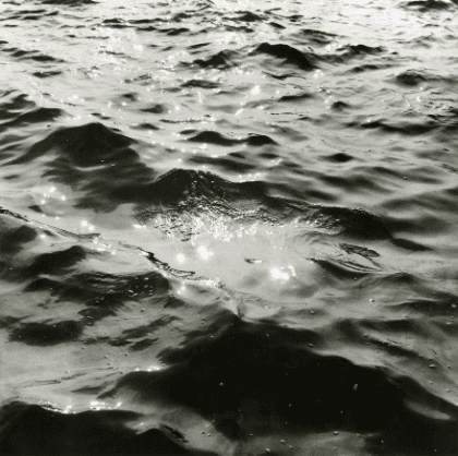 Black-and-white photograph of a water surface in close-up, with light reflecting on it.