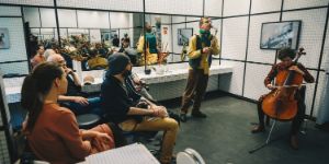 Ein Ensemble spielt in einem gefließten Raum mit vielen Spiegeln