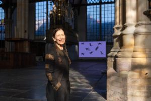 Meredith Monk in einer Kirche, sie trägt zwei geflochtene Zöpfe