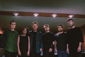 Gruppenfoto der Deranged Particles. Über ihnen runde Deckenleuchten.