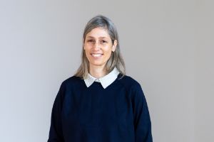 Porträt von Patrizia Dander. Sie lächelt, trägt Jeans und einen Pullover.