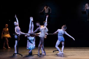 Dancers in various positions at a barre