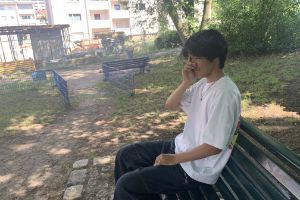 Portrait of Subinn sitting on a park bench and holding a handkerchief to his eye