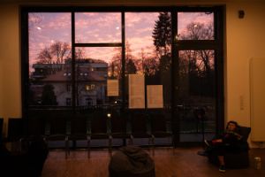 A person is sitting in an armchair in front of a window at dusk.
