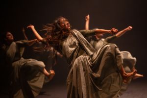 In powerful and exaggerated gestures, three performers take a step forward.