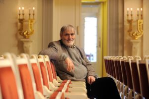 Ein Mann sitzt in der leeren Stuhlreihe im Konzerthaus Berlin und schaut in die Kamera.