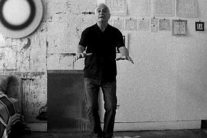 Filmstill aus Rirkrit Tiravanijas "untitled 2008 (john giorno reads)", auf dem der Künstler John Giorno in die Kamera gestikuliert.