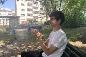 Portrait of Raphaël sitting on a park bench and applauding