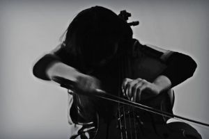 Schwarz-weiß-Bild mit leicht verschwommenen Konturen: Eine Person spielt Cello.