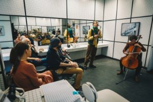 Ein Ensemble spielt in einem gefließten Raum mit vielen Spiegeln