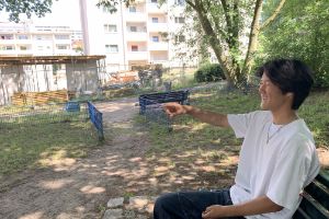 Portrait of Subinn sitting on a park bench and pointing