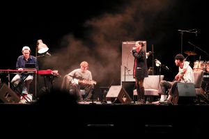 Eine vierköpfige Band bestehend aus Keyboarder, Gitarrist, Bassist und Sängerin spielt auf einer Bühne.