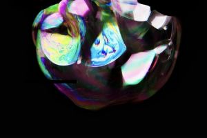 Eine schillernde gefaltete Papierkugel schwebt vor schwarzem Hintergrund.