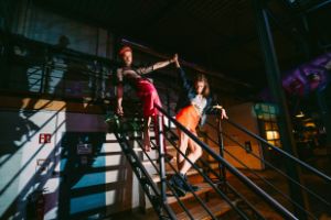 Zwei Personen stehen auf einer Treppe und verschränken ihre Hände in der Luft.