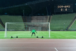 A goalkeeper in a goal in front of an empty stadium