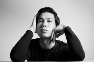 Alex Koo stützt seinen Kopf mit seinen Händen ab.