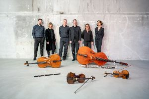 Das Ensemble steht an einer Wand. Ihre Instrumente liegen vor ihnen auf dem Boden.