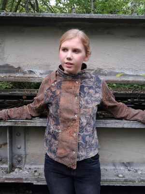 Eine junge Person steht mit seitlich abgelegten Armen und schaut in die Ferne.