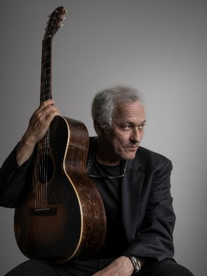 Marc Ribot post mit seiner Gitarre, die Farben wirken düster.