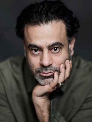 Porträt von Samir Odeh-Tamimi, das Kinn in die Hand gestützt. Odeh-Tamimi hat schwarze Haare und einen kurzen Bart.