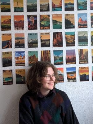 Fanny Marek Walger sitzt vor einer Wand voller Postkarten und schaut in die Ferne.