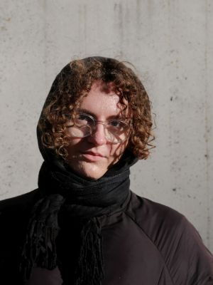 Person mit lockigen Haaren schaut in die Kamera.