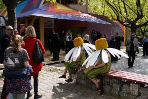 People dressed as daisies sit on a bench