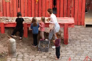 Children stand in front of a table covered with sand and dig