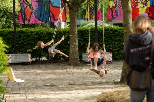 Children play on swings between trees