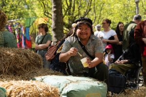 A man, sitting on a mountain of straw bales, has a brush and paint in his hand