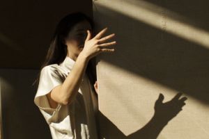 A person stands in front of stretched fabric on which a shadow falls.