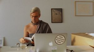 Filmstill aus Rirkrit Tiravanijas "Karl’s Perfect Day", das den Künstler Karl Holmqvist lesend an einem Schreibtisch zeigt.