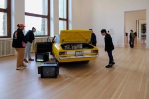 Installationsansicht von Rirkrit Tiravanija's "untitled 1995 (bon voyage monsieur ackermann)" mit Besucher*innen im Rahmen der Ausstellung "Rirkrit Tiravanija: DAS GLÜCK IST NICHT IMMER LUSTIG" im Gropius Bau.