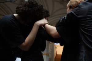 Nahaufnahme von mehreren Menschen, die sich an ihren Köpfen und Schultern berühren. Es sind keine Gesichter zu sehen.