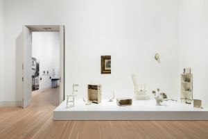 White furniture, divided into two parts, stands on a pedestal.