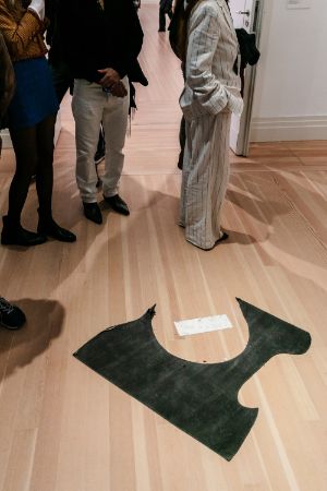 Black fabric with footprints on the floor, a small sign next to it.